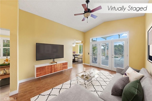 living room with ceiling fan, light hardwood / wood-style flooring, lofted ceiling, and french doors