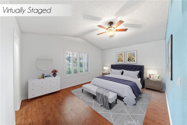 bedroom with ceiling fan, hardwood / wood-style floors, a textured ceiling, and lofted ceiling