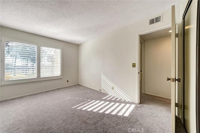 spare room featuring a textured ceiling and light carpet