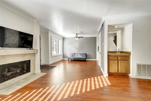 unfurnished living room featuring ceiling fan, a fireplace, ornamental molding, and hardwood / wood-style flooring