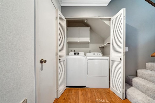 laundry area featuring cabinets, light wood-type flooring, ornamental molding, and washing machine and clothes dryer