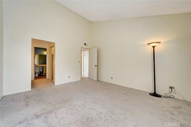 carpeted spare room with high vaulted ceiling