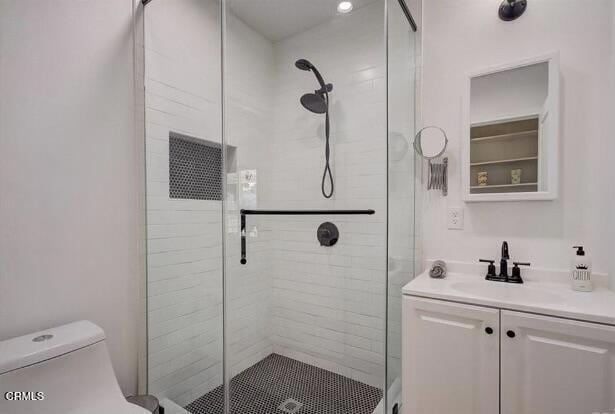 bathroom with toilet, a shower with door, and vanity