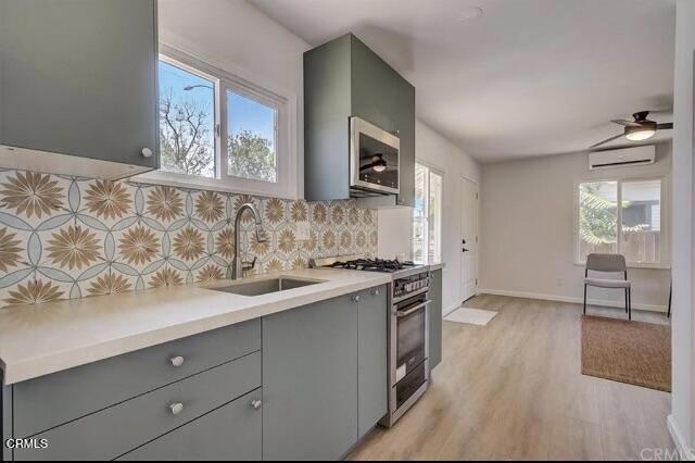 kitchen featuring decorative backsplash, sink, high end stove, ceiling fan, and light hardwood / wood-style flooring