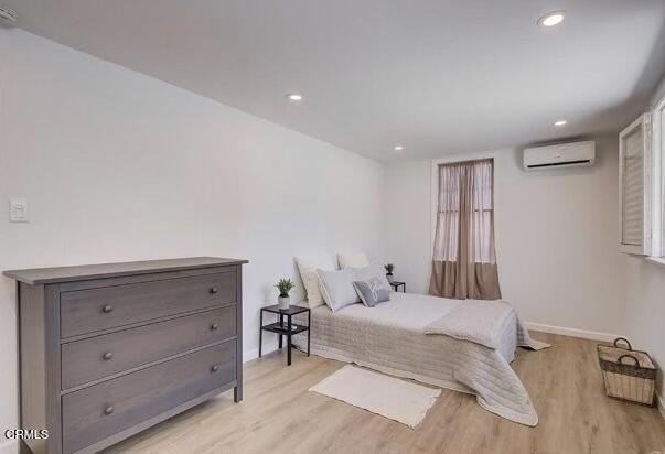 bedroom featuring light wood-type flooring and a wall mounted air conditioner