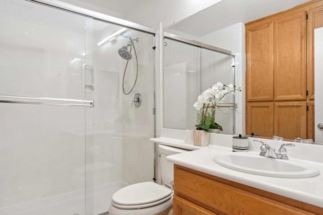 bathroom with toilet, a shower with shower door, and vanity