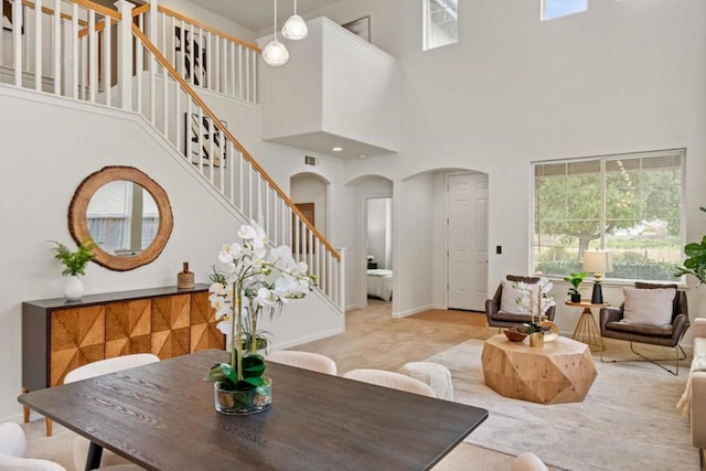 dining space with light carpet and a towering ceiling