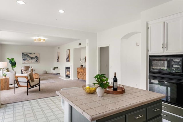 kitchen featuring light carpet, tile countertops, and black appliances