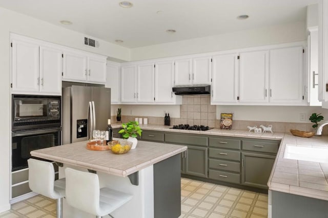 kitchen featuring sink, white cabinets, black appliances, and tile countertops