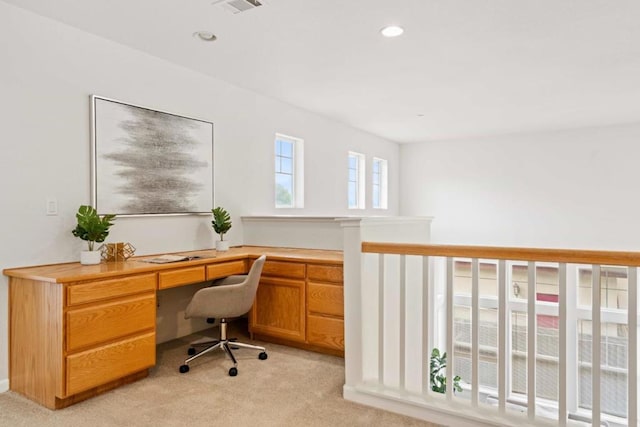 office space with built in desk and light colored carpet