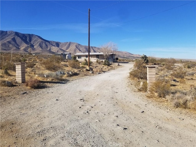 view of street with a mountain view and dirt driveway