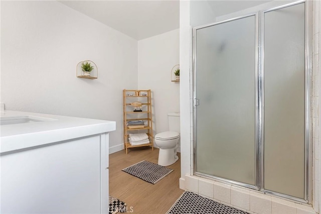 bathroom featuring hardwood / wood-style floors, an enclosed shower, vanity, and toilet