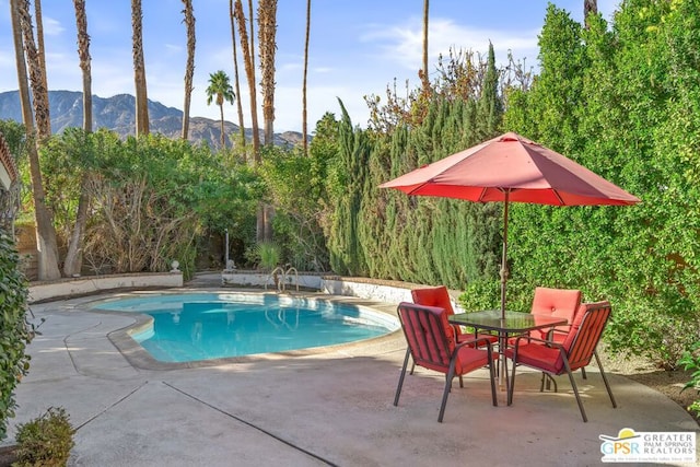 view of swimming pool with a mountain view and a patio