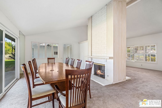 carpeted dining area featuring a fireplace, plenty of natural light, and lofted ceiling