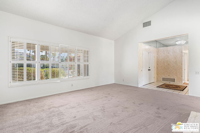 carpeted spare room with high vaulted ceiling