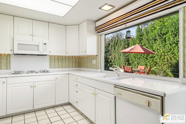 kitchen with tasteful backsplash, sink, light tile patterned floors, white appliances, and white cabinets