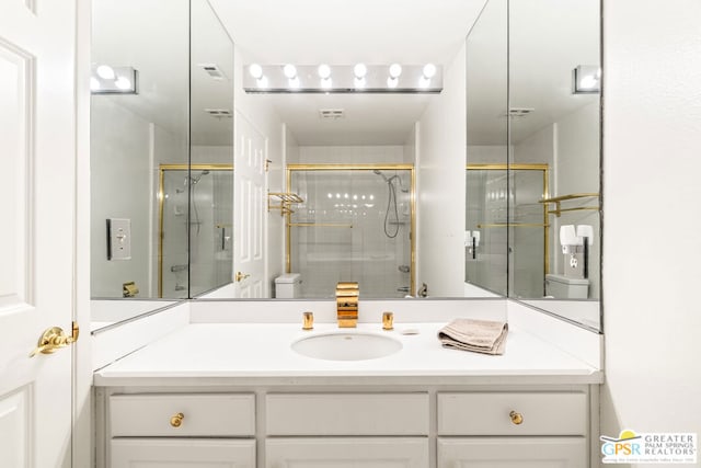 bathroom featuring a shower with shower door, vanity, and toilet