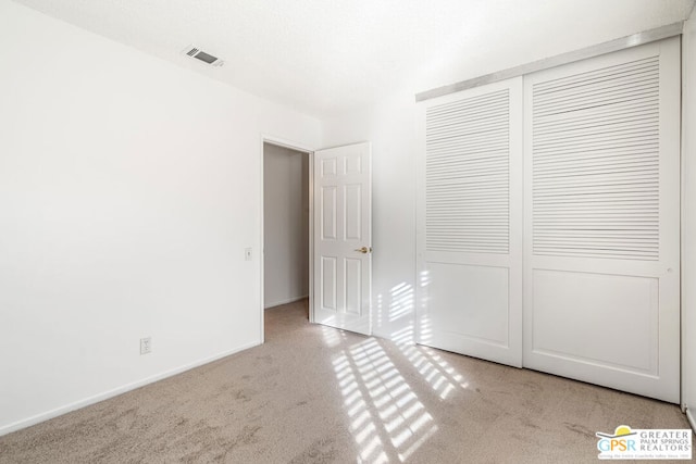 unfurnished bedroom with light carpet and a closet