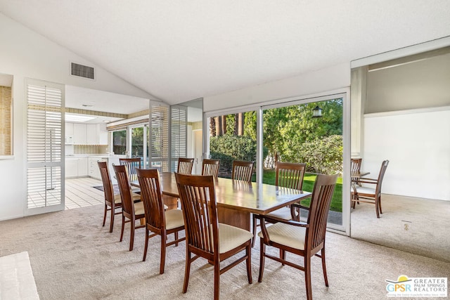 dining room featuring light colored carpet and vaulted ceiling