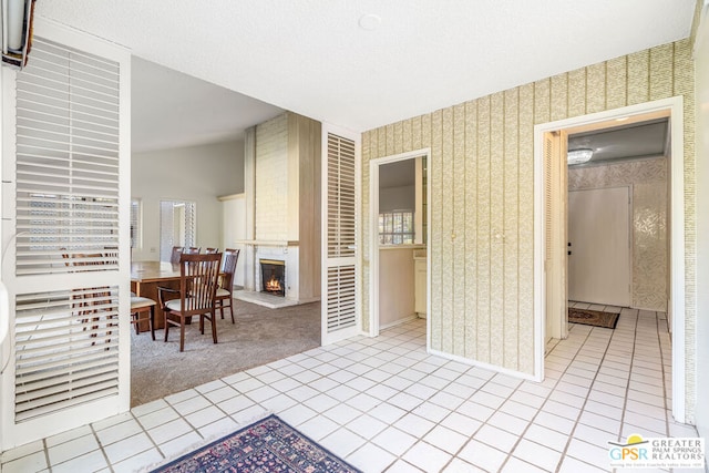 interior space with light carpet, a large fireplace, and tile countertops