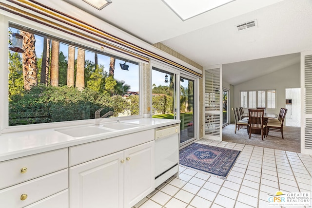 kitchen featuring white cabinets, sink, vaulted ceiling, white dishwasher, and light colored carpet