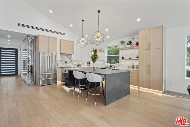 kitchen with appliances with stainless steel finishes, a center island, decorative backsplash, light hardwood / wood-style floors, and a breakfast bar