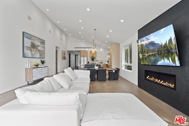 living room featuring light wood-type flooring and high vaulted ceiling