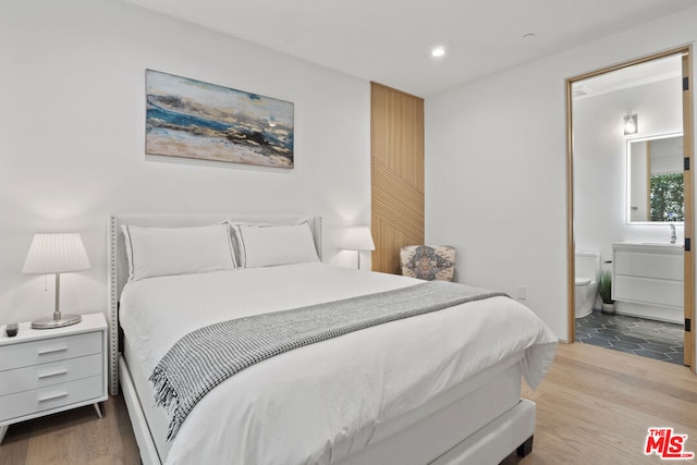 bedroom with light hardwood / wood-style floors and ensuite bath