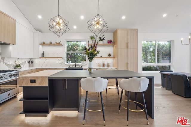 kitchen featuring light wood-type flooring, a kitchen island, a kitchen bar, and high end range