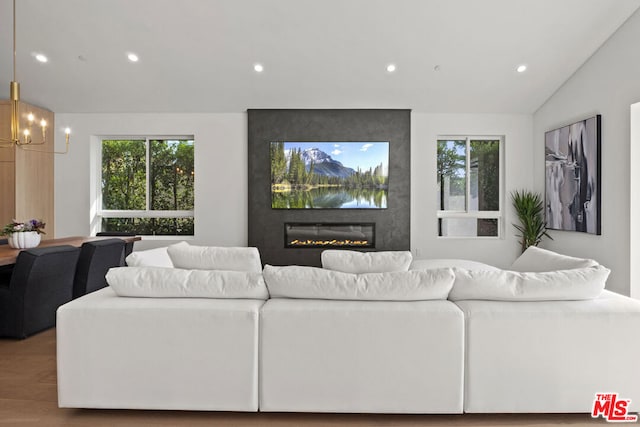 living room with vaulted ceiling, an inviting chandelier, a fireplace, and hardwood / wood-style flooring