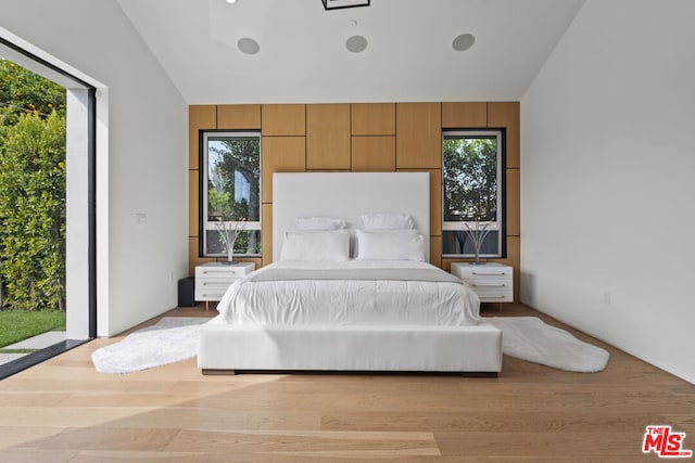 bedroom with vaulted ceiling, access to exterior, and light hardwood / wood-style floors