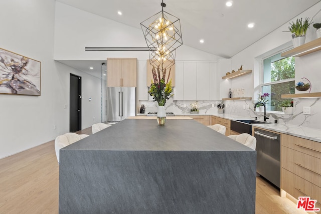 kitchen featuring a center island, stainless steel appliances, backsplash, hanging light fixtures, and light hardwood / wood-style flooring