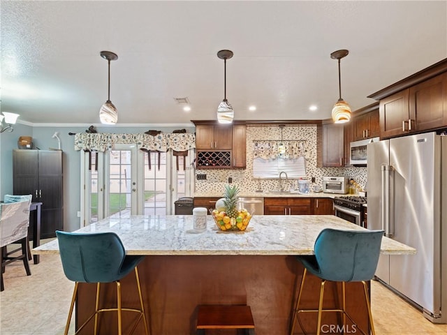 kitchen featuring a center island, sink, stainless steel appliances, and pendant lighting