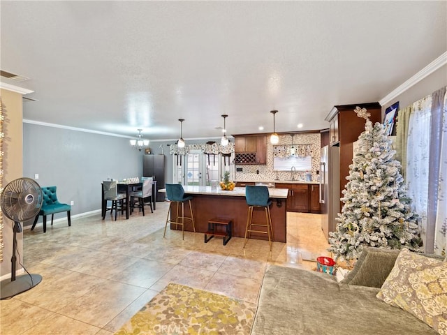 kitchen featuring pendant lighting, a center island, tasteful backsplash, a breakfast bar, and crown molding