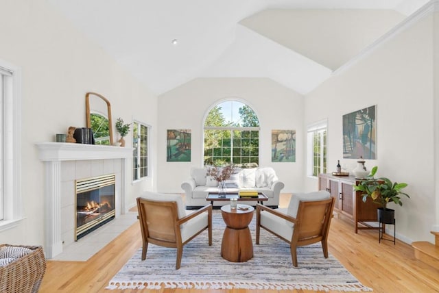 sitting room featuring light hardwood / wood-style floors, a tiled fireplace, and vaulted ceiling