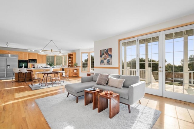 living room with french doors, track lighting, and light hardwood / wood-style flooring