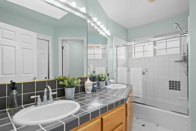 bathroom with tile patterned floors, vanity, combined bath / shower with glass door, and decorative backsplash