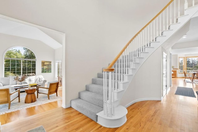 stairs with a towering ceiling and wood-type flooring