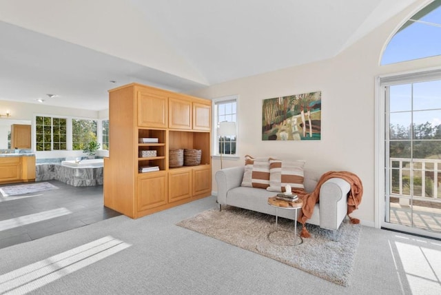 living room with vaulted ceiling, a healthy amount of sunlight, and light colored carpet