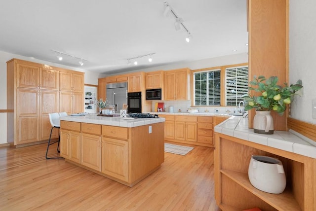 kitchen with tile countertops, light wood-type flooring, and black appliances