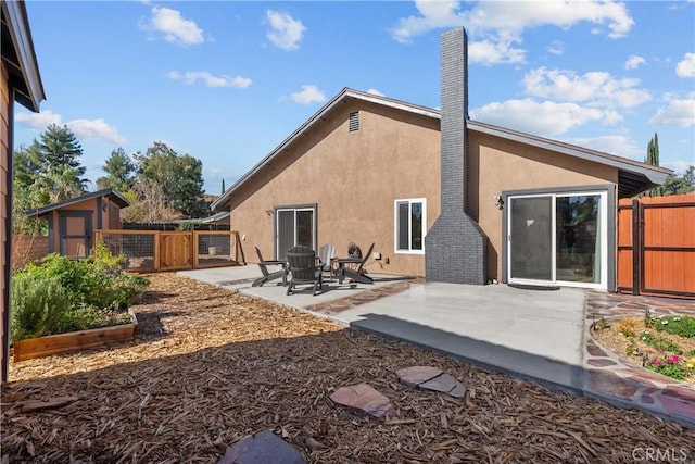 rear view of house with a storage shed and a patio