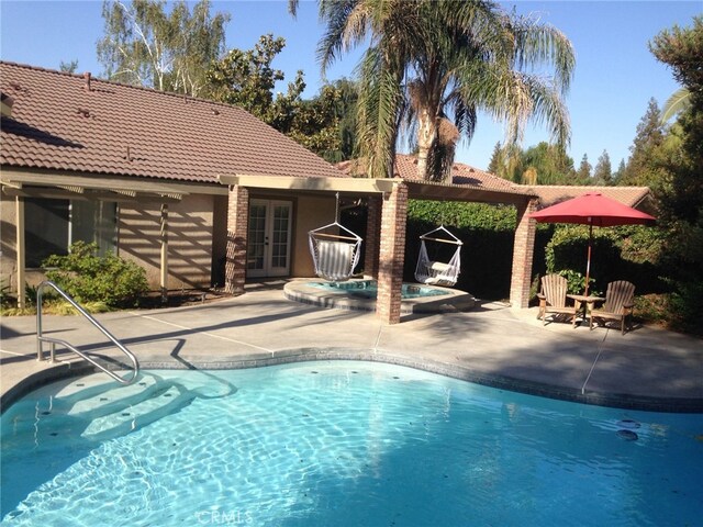 view of pool with french doors, a patio area, and a jacuzzi