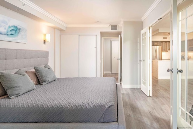 bedroom with stainless steel fridge, light wood-type flooring, a closet, french doors, and crown molding