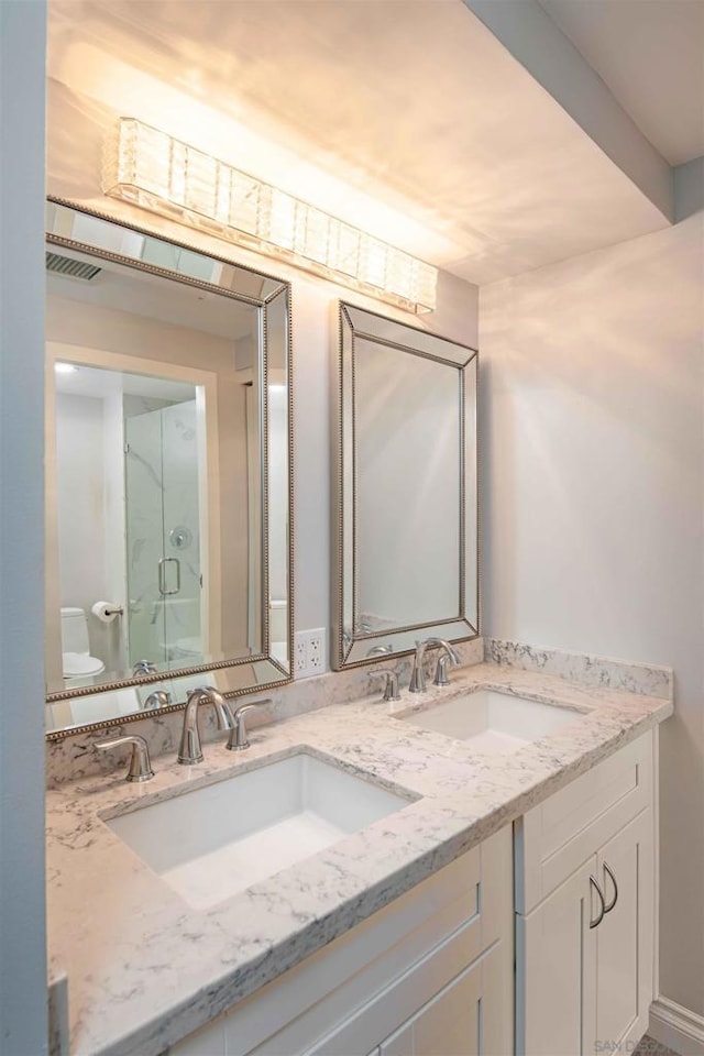 bathroom featuring toilet, vanity, and a shower