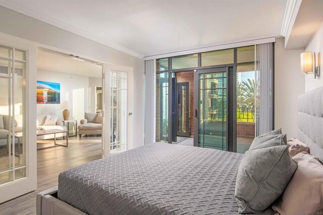 bedroom featuring hardwood / wood-style flooring, access to exterior, crown molding, and french doors