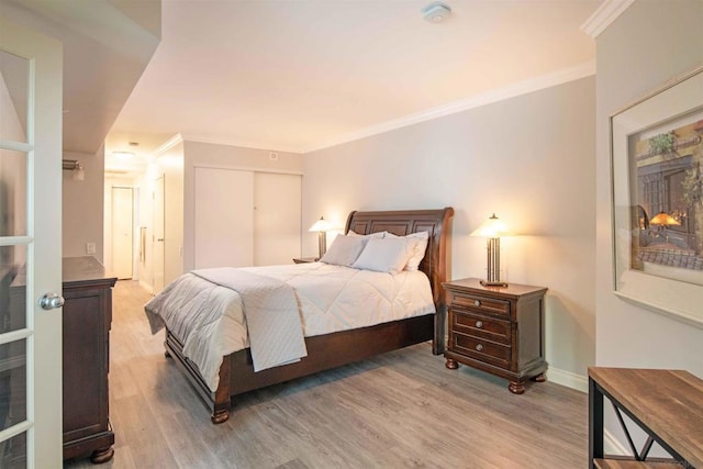 bedroom featuring a closet, ornamental molding, and light hardwood / wood-style flooring