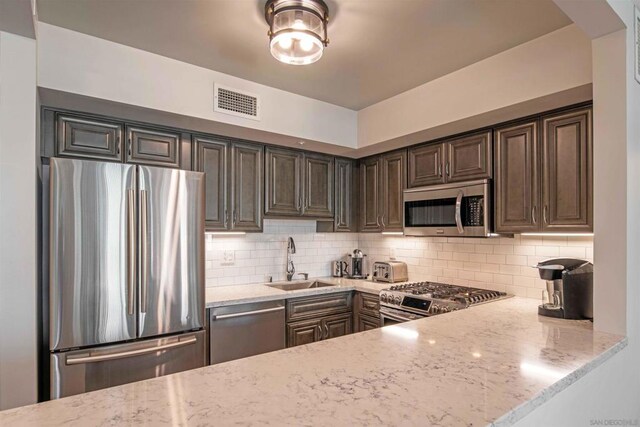 kitchen featuring light stone counters, sink, appliances with stainless steel finishes, and tasteful backsplash