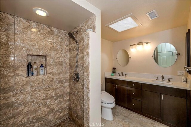 bathroom featuring toilet, tiled shower, and vanity