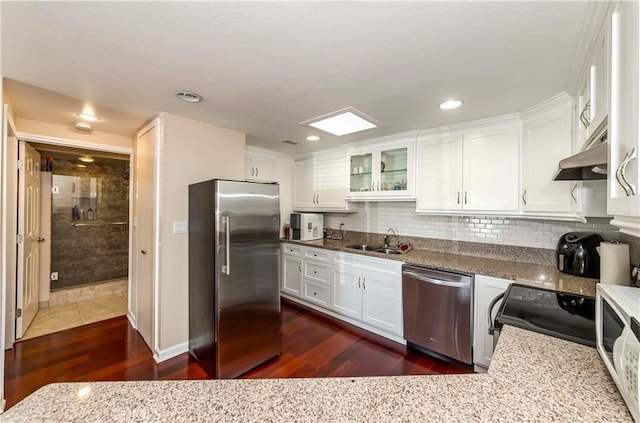 kitchen with sink, light stone counters, stainless steel appliances, and white cabinetry