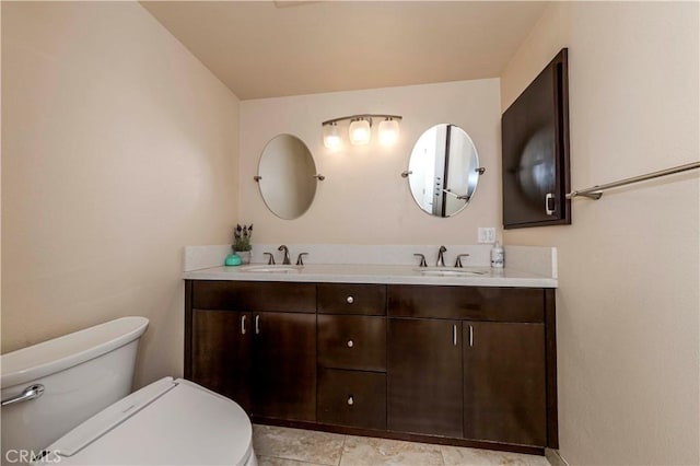 bathroom with toilet, vanity, and tile patterned flooring